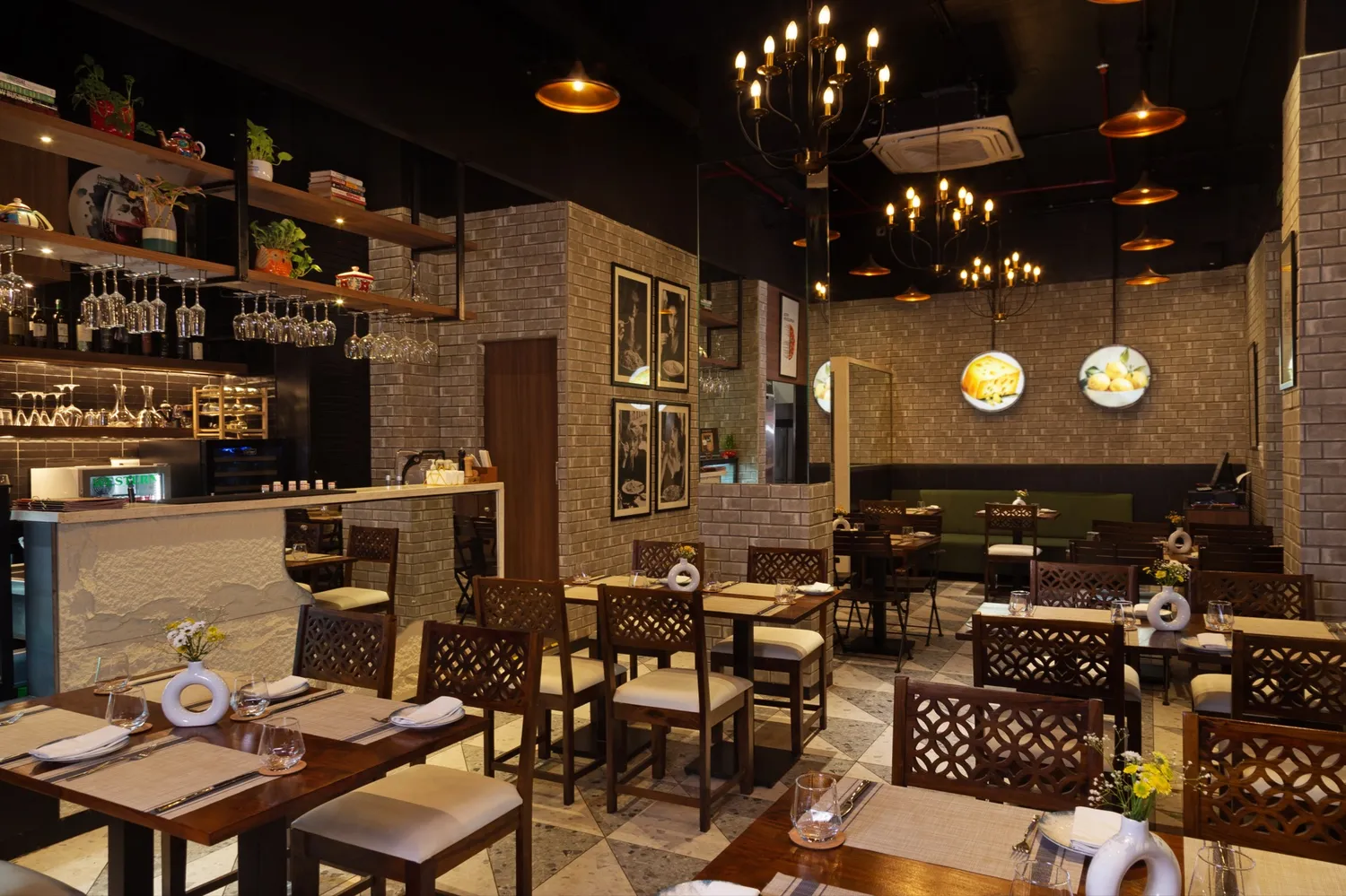 The candlelit dining room at Rosmarino, Indiranagar — exposed brick, chandeliers, framed prints and rustic wood